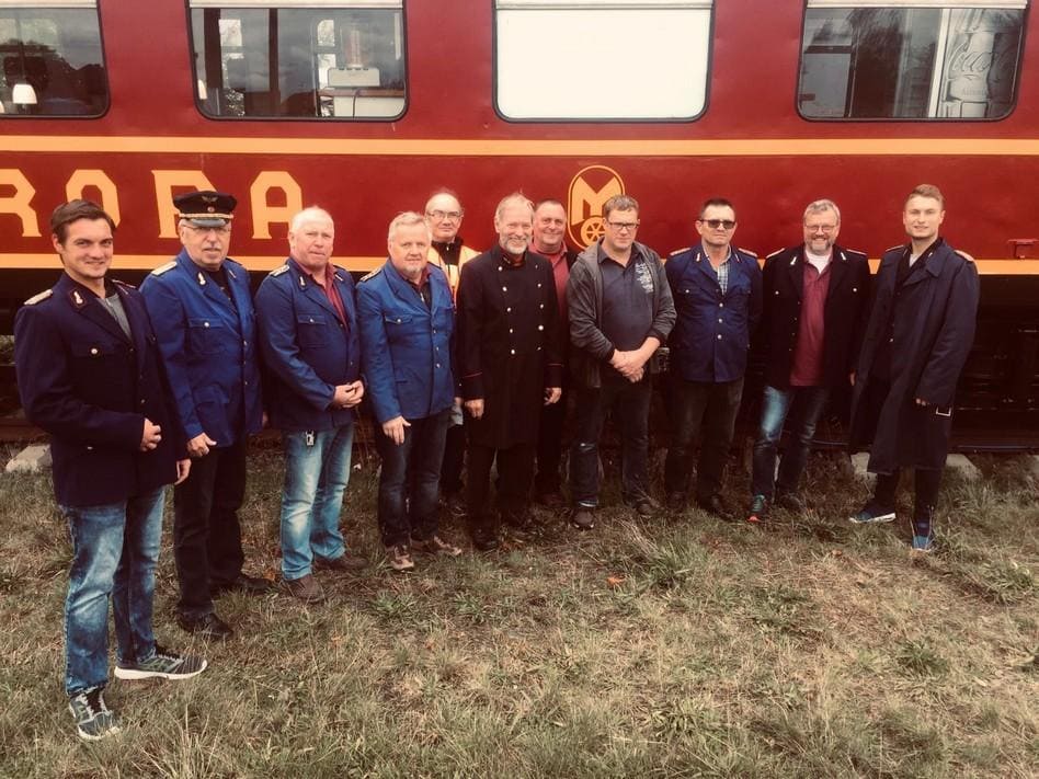 Mitglieder des Kleinbahnvereins Rothenburg/O.L. e.V. vor einem historischen Wagen.